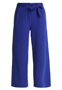 Pantalons larges en tissu bleu vif avec une texture lisse. Dotés d'une ceinture à nouer à la taille et de deux poches avant.