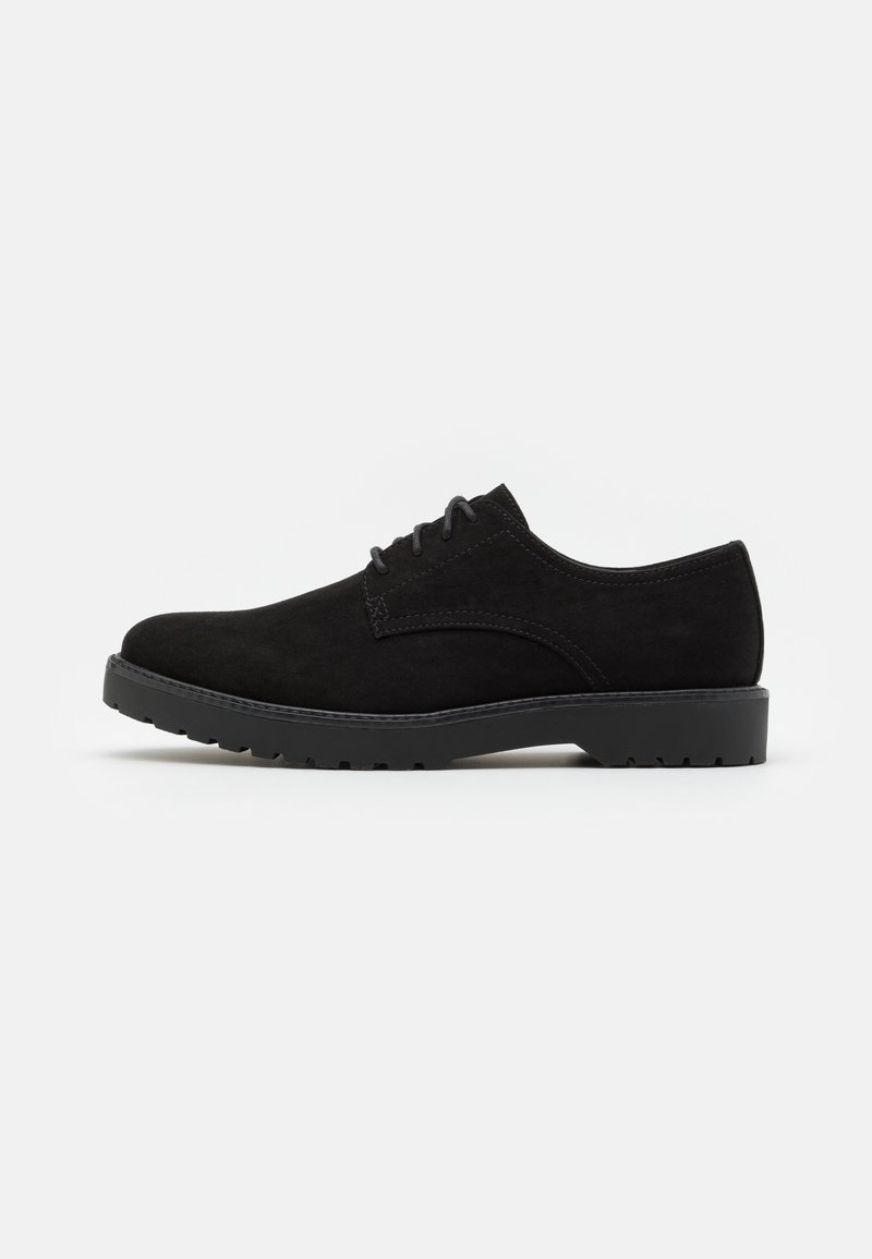 Chaussure en daim noir avec un bout arrondi, un design à lacets plats et une semelle extérieure texturée dotée de petites grips uniformes pour une traction optimale.