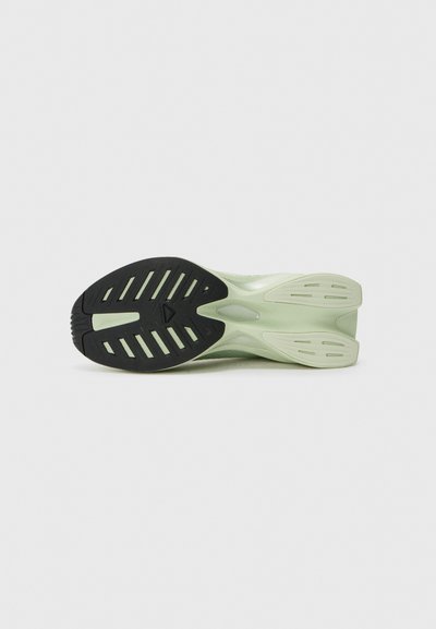 Grüne Sport-Schuhsohle mit einer strukturierten schwarzen Gummisohle, die Rillen und Lüftungsöffnungen für Traktion und Belüftung aufweist. Glattes, flexibles Material.