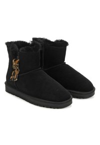 Botines de ante negros con forro de piel de peluche, que presentan un acento decorativo de hardware en el lateral. Suela plana, textura suave y diseño de punta redonda.