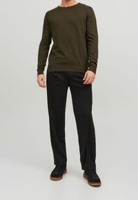 Maglione girocollo verde oliva, dalla texture interessante, con maniche lunghe, abbinato a pantaloni neri a vestibilità semplice e scarpe nere con suola in gomma.