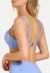 Jasnoniebieski biustonosz o gładkiej fakturze, z regulowanymi ramiączkami i zapięciem na plecach. Zaprojektowany w minimalistycznym stylu.