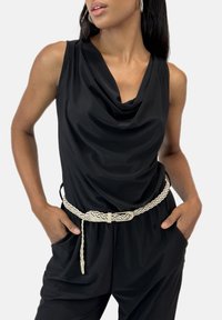 Top negro sin mangas con un escote drapeado, combinado con un cinturón de fibra de color marfil. Tela suave con un corte relajado y bolsillos laterales.