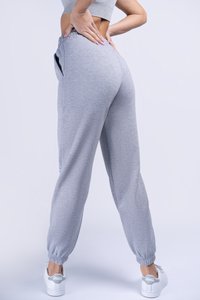 Gray sweatpants with a relaxed fit, elastic waistband, side pockets, and cuffed hems, paired with white sneakers.