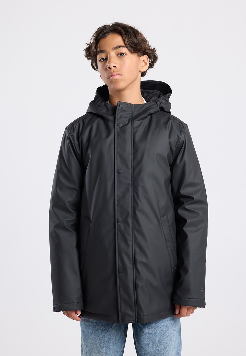 Black waterproof jacket with a hood, featuring snap closures, side pockets, and a smooth, shiny texture. Worn over blue jeans.