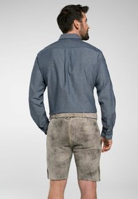 Heren blauwe lange mouwen overhemd met een geweven patroon en knoopmanchetten, gecombineerd met grijze suède shorts met een zijzak en riemlussen.