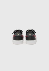 Baskets noir et blanc avec des accents rouges, matériau supérieur en synthétique lisse, design à lacets et semelle en caoutchouc blanc avec logo en relief.