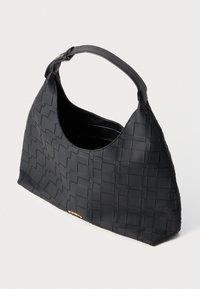 Sac à main tissé noir avec une silhouette courbée, fabriqué en matériau texturé. Dispose d'une seule bandoulière et d'un petit logo doré.