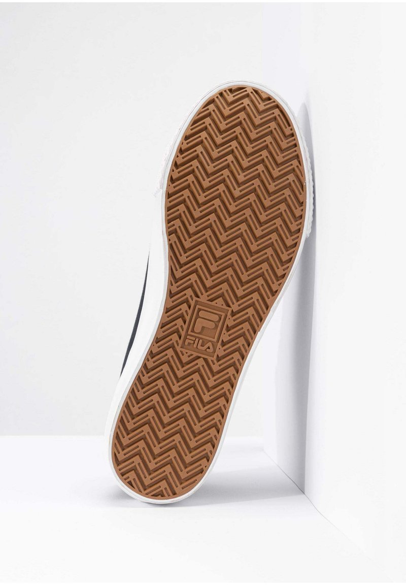 Suela de zapatilla blanca con un patrón de espiga de goma marrón. Presenta un logo de FILA prominente en el centro. Bordes suaves y diseño de agarre texturizado.