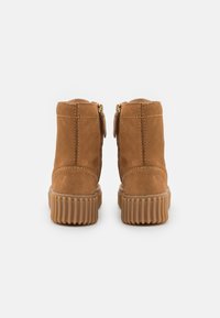 Sukaneet nahkaisen ankle-boots -malliset kengät, joissa on sileä pinta, vetoketjukiinnitykset kummallakin puolella ja uritettu ruskea kumipohja.