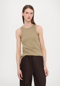 Khaki brezrokavni top iz rebraste tkanine, v kombinaciji s temnimi nabranimi hlačami. Top ima okroglo ovratnico in sproščen kroj.