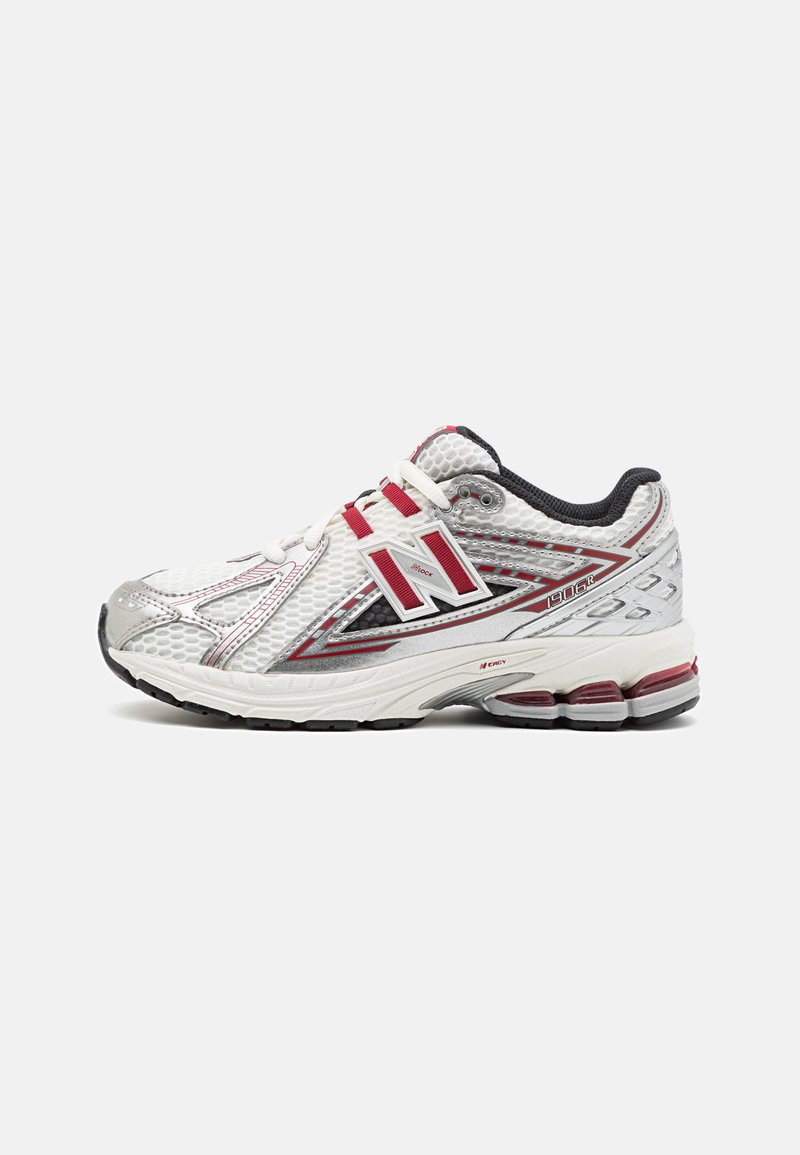 Chaussure de sport blanche avec des accents argentés et des détails rouges. Tige en maille, semelle amortissante, et marque distinctive sur le côté.