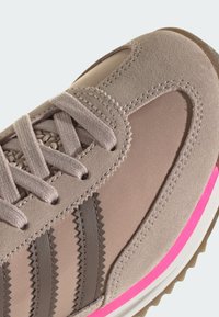 Béžová teniska s vrškem z semiše a textilu, obsahující tři hnědé cikcak pruhy, světle růžové detaily, texturovaný povrch a tkaničky.