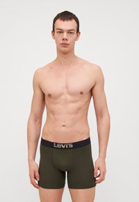 Levi's grüne Boxershorts mit einem schwarzen Bund, der ein Logo trägt. Der Stoff ist glatt und eng anliegend, konzipiert für Komfort und Unterstützung.