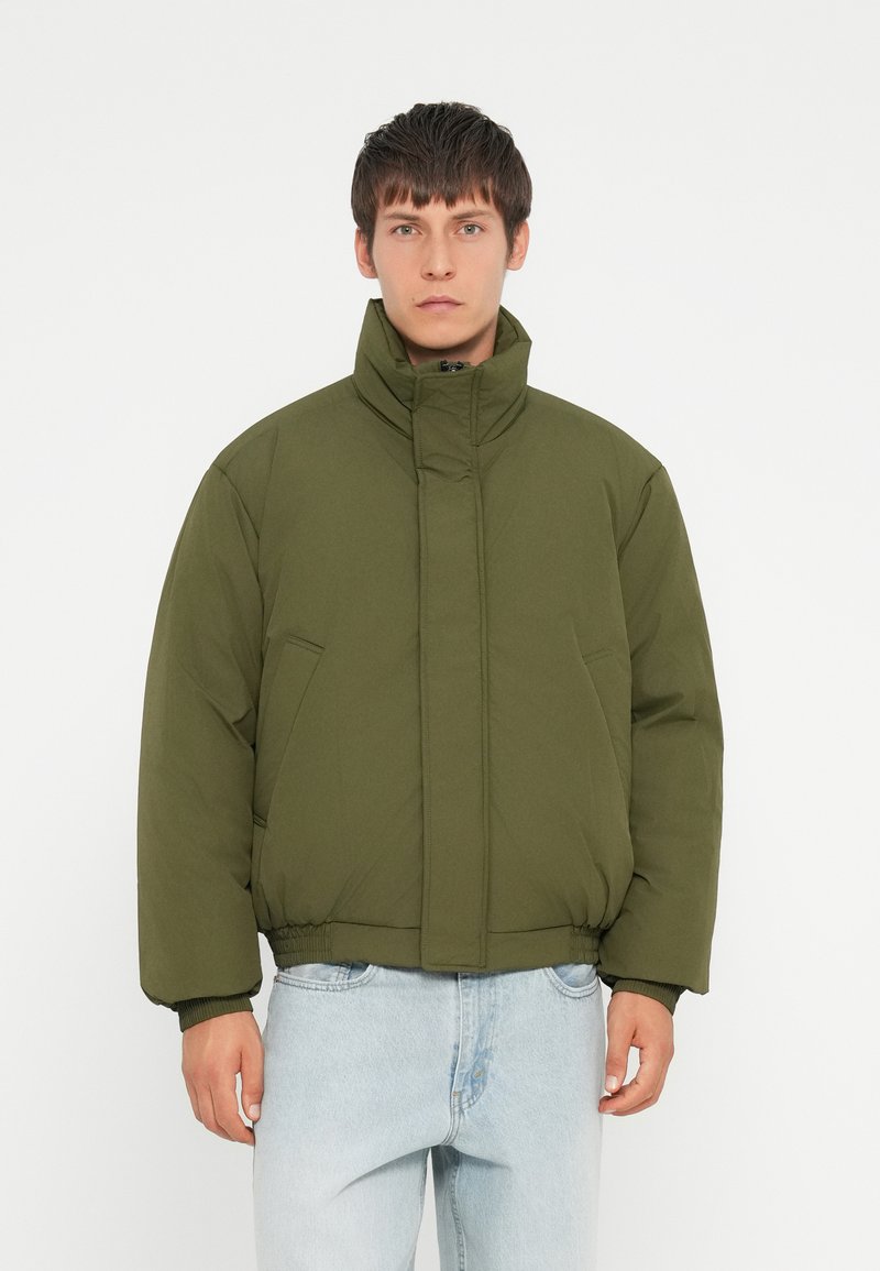 Olive green padded jacket with a high collar, front zipper, and elastic cuffs. Features two side pockets and a cropped design.