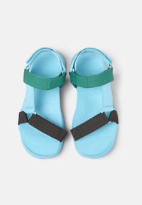 Blå gummiskor med gröna och svarta nylonremmar. Platt design med texturerade innersulor för grepp. Justerbart remsystem för passform.