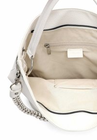 Biała skórzana torebka o fakturowanej powierzchni, z kontrastującym czarnym zamkiem błyskawicznym i srebrnymi elementami metalowymi. Wnętrze wyposażone w kieszeń na zamek i dużo miejsca.