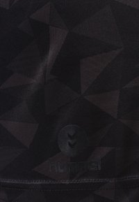 Černá sportovní tkanina s geometrickým vzorem trojúhelníků. Obsahuje texturované logo v dolním rohu. Hladký povrch, bez dalších akcentů.