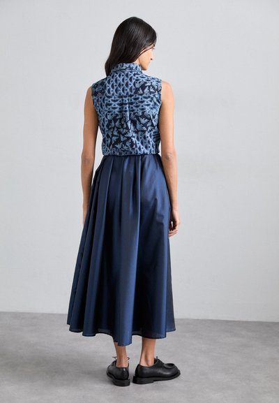 Navy dress featuring a sleeveless, patterned bodice and a full, pleated skirt. Smooth fabric with a textured top and solid bottom.