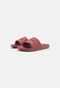 Sandale de plajă roz din cauciuc fin, cu un brâu lat care poartă logo-ul "Calvin Klein" și o talp�ă texturată pentru confort.