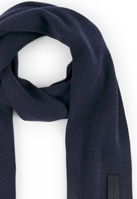 Granatowy dziany szalik o miękkiej fakturze, charakteryzujący się prostym wzorem i prostokątnym kształtem. Zawiera prostokątną skórzaną metkę.