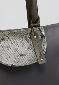 Torebka z klapką w szarym i czarnym wzorze węża, ciemnozielony skórzany pasek oraz małe metalowe logo w kształcie skrzydlatego serca na przodzie.