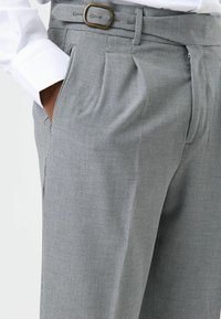 Grijze broek met patroon en plooien, met een gladde textuur, zijzakken en een bronzen gesp in de taille.