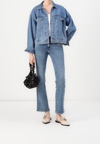 Chaqueta vaquera de manga larga, vaqueros de corte recto, mocasines beige con detalles decorativos y un bolso negro con estampado floral.