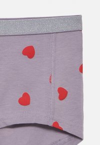 Lenjerie de culoare mov cu imprimeuri mici în formă de inimă roșie, având o bandă elastică argintie lucioasă și detalii vizibile de cusătură. Material moale din bumbac.