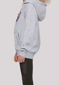 Felpa grigia con tasca a marsupio, decorata con una grafica colorata sul davanti, abbinata a leggings neri con dettagli in rete.