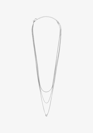 Zilveren meerlagige ketting met drie kettingen van verschillende lengtes, waarbij de kortste ketting is versierd met een cirkelvormige hanger en detail.