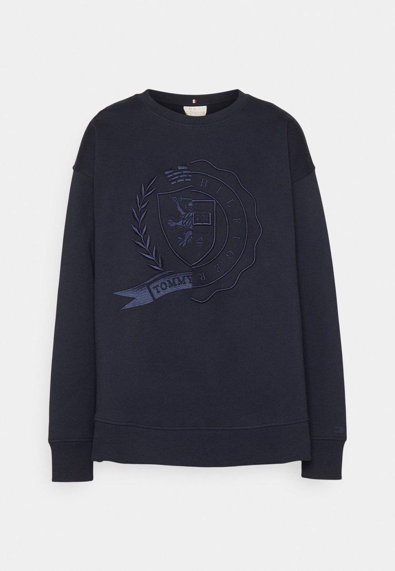 Sudadera azul marino con un diseño de escudo bordado en relieve, mangas largas y puños y bajo de canalé. Corte casual con un cuello redondo clásico.