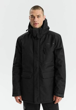 Czarna kurtka na zewnątrz z wysokim kołnierzem, zapinana na zamek, z wieloma kieszeniami. Materiał wydaje się trwały i wodoodporny. Posiada minimalistyczny design.