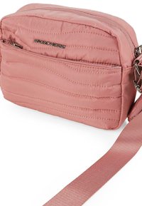 Bolso cruzado rosa hecho de tejido acolchado, con acentos de cremallera plateada, un logotipo en la parte frontal y una correa de tela ajustable.