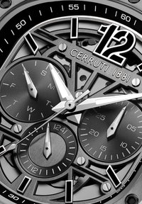 El reloj Cerruti 1881 presenta un diseño en negro y plata, una esfera intrincada con patrones circulares, manecillas plateadas y un prominente número 12.