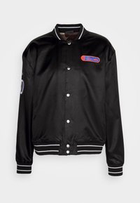 Black satin bomber jacket with white stripes on the collar and cuffs, featuring a red and blue logo patch on the chest and snap button closure.