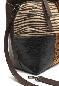 Läderhandväska med en blandning av texturer: zebra tryck i päls, svart krokodilprägling och leopardmönstrad tyg med bruna accenter.