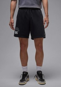 Zwarte katoenen korte broek met een elastische tailleband, voorzien van een witte "Jordan 84"-grafiek. Draag met zwarte en grijze sneakers en witte crew-sokken.