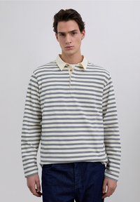 Polo de manga larga blanca con rayas horizontales en azul marino, cuello en beige claro, tapeta de tres botones, material de algodón suave, ajuste relajado.