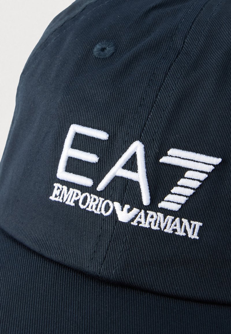Gorra azul marino de tela texturizada con el logo bordado en blanco "EA7 EMPORIO ARMANI" y un diseño cosido en el panel frontal.