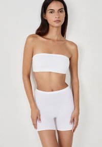 Vit bandeau-topp och högmidjade shorts i mjukt, stretcht tyg. Enkelt design med sömlösa kanter och en figurnära siluett.