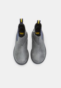 Botas de tobillo grises con una textura suave y punta redondeada. Presentan un acento azul y una tira amarilla en la parte trasera. Cierre con cremallera en el lateral.