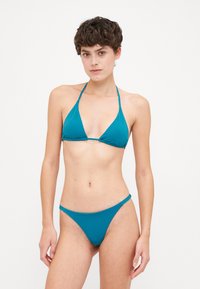 Teal bikini sett som har en trekantformet topp med minimalt stoff og tynne stropper, supplert med matchende lavhalsede bunnplagg. Glatt tekstur.