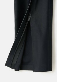Pantaloni neri su misura con chiusura laterale a zip e design slim fit. Il materiale ha una texture liscia con una finitura pulita.