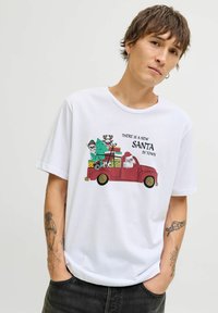 Camiseta de algodón blanca con un gráfico de un camión vintage rojo, con un Santa Claus de dibujos animados y regalos, texto "HAY UN NUEVO SANTA EN LA CIUDAD." Manga corta.