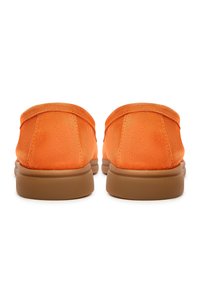 Chaussures en daim orange à enfiler avec un dos arrondi et une semelle en caoutchouc marron. Texture lisse avec des détails de couture subtils.