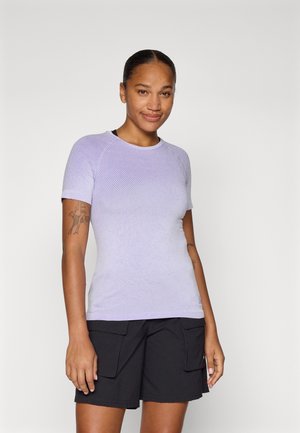 Top scurt ajustat de culoare violet deschis, cu un model texturat. Dispune de un decolteu rotund și mâneci raglan. Este purtat cu pantaloni scurți cargo negri.