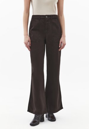 Brązowe spodnie o szerokich nogawkach z wysokim stanem, przednimi kieszeniami i prostym krojem. Wykonane z miękkiego, teksturowanego materiału, z widocznym zapięciem na guziki.