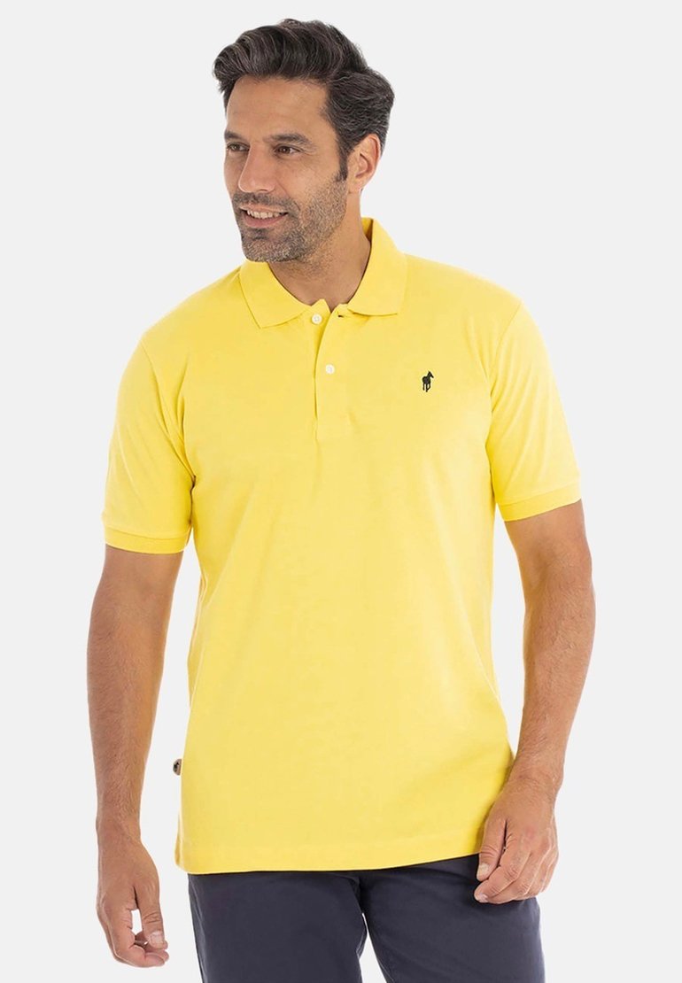 Polo shirt jaune en coton, avec un col et des manches courtes. Emblème noir sur la poitrine. Design simple avec une texture lisse.