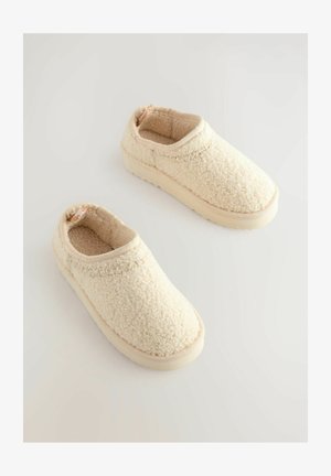 Chaussures à enfiler en crème floue avec une surface texturée et doublure rembourrée, dotées d'une semelle en caoutchouc et d'un col élastique pour un enfilage facile.